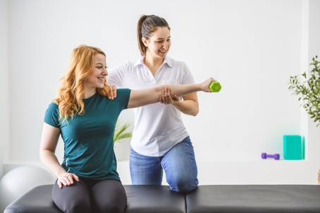 Woman smiling while focusing on physical therapy exercises with her provider. She is benefitting from both the physical and mental benefits of physical therapy. | ProFysio PT